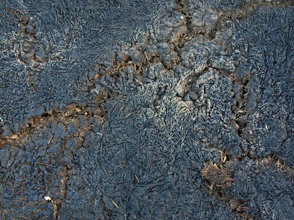 Verlassene Brandstelle. verbranntes Gras erstarrte im Regen zu Schlamm und verwandelte sich dann in rissigen trockenen Lehm. — Stockfoto