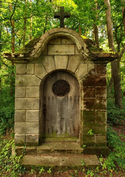 Old traditional village chapel in the park at old graveyard in shadows of old alder trees and lindens. Door with rusty forged gate is closed. — Stock Photo, Image