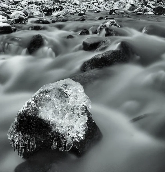 's avonds winter weergeven ijspegels, ijzige takken en rotsen in het koelen van de stroom. reflecties in ijspegels, vervagen witte schuim. — Stockfoto