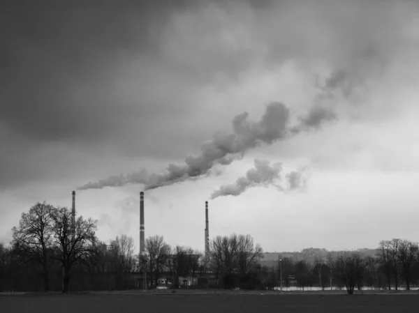 Três chaminés fumantes, fumaça cinza e nuvem escura tempestuosa acima da planta . — Fotografia de Stock