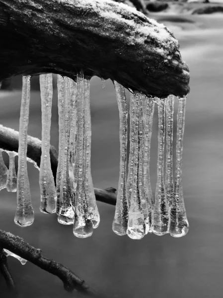 's avonds winter weergeven ijspegels, ijzige takken en rotsen in het koelen van de stroom. reflecties in ijspegels, vervagen witte schuim. — Stockfoto