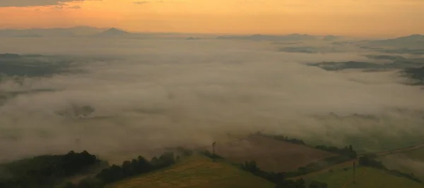 View into foggy countryside with bushes, forests, villages, levels of ponds within early morning sunrise. — Stock Photo, Image