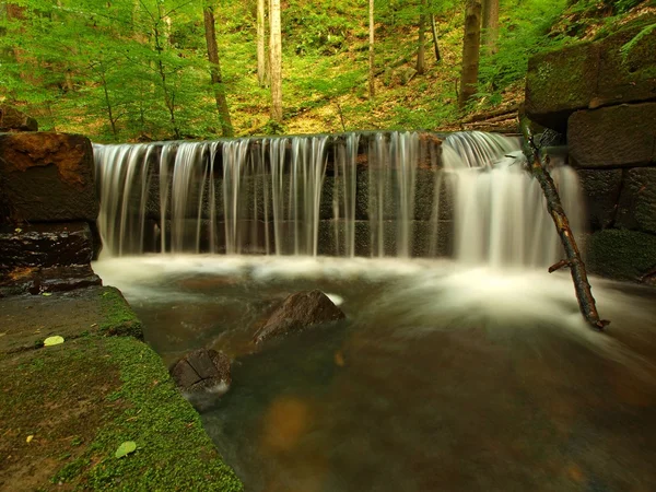 Kleines Wehr am Bergbach, Wasser läuft über Basaltsteine. — Stockfoto