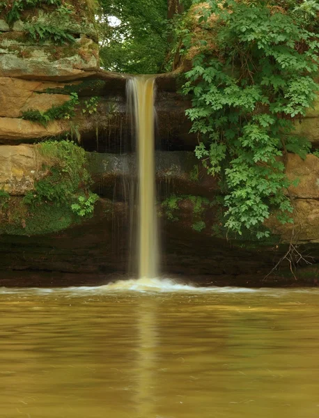 Vattenfall av grumligt vatten i bruna damm. — Stockfoto