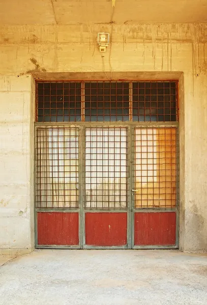 Altes rostiges Garagentor, Glas mit rostigen Gittern überzogen, raue Betonwand ringsum. — Stockfoto
