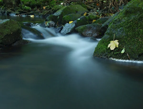 Kaskade auf kleinem Gebirgsbach, Wasser läuft über Basaltsteine und Blasen bilden sich auf ebenem milchigen Wasser. — Stockfoto