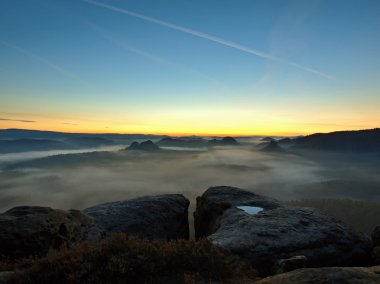saxon'ın derin puslu vadide görünüme İsviçre. kumtaşı doruklarına sisli arka plandan arttı, sis nedeniyle sunrise orange olduğunu.