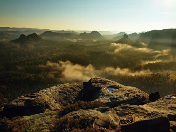 Sunrise in a beautiful mountain of Czech-Saxony Switzerland. Sandstone peaks increased from foggy background, the fog is orange due to sun rays. — Stock Photo, Image