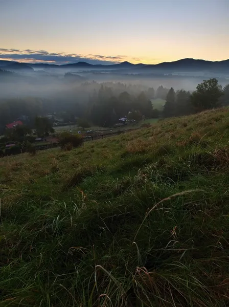 Vue sur la vallée brumeuse profonde d'automne dans le parc national de Bohême, en Europe. Les arbres et les collines ont augmenté à partir du fond brumeux. Ciel coloré au-dessus de l'horizon . — Photo