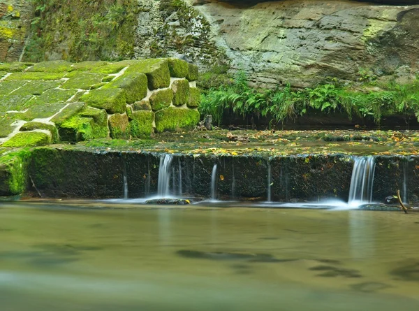 Ruïnes van zandsteen weir op kleine berg rivier. Stream is stroomt over zandsteen blokken en maakt melkachtig water. — Stockfoto