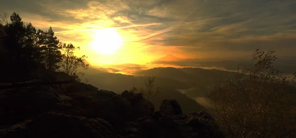 Wschód słońca w piękne góry Szwajcarii Czesko Saksonia. Piaskowiec szczyty i wzgórza wzrosła z mglisty tło, mgła jest pomarańczowy z promieni słonecznych. — Zdjęcie stockowe