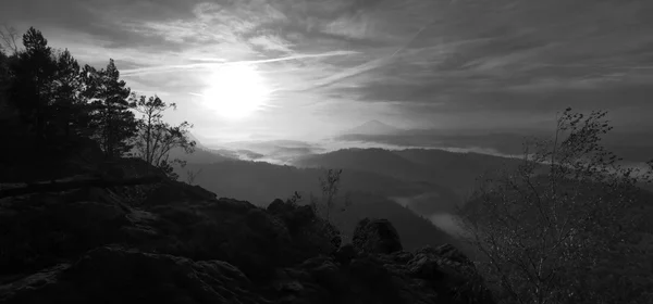 Lever de soleil dans une belle montagne de Bohême-Saxe Suisse. Les sommets et les collines de grès ont augmenté à partir du fond brumeux. Premiers rayons du soleil. Photo en noir et blanc . — Photo