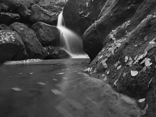 Water spray below small waterfall on mountain stream, water is falling over mossy sandstone boulder. The spray create on level and gravel milky water. — Stock Photo, Image