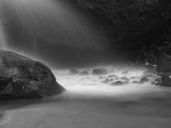 Water spray below small waterfall on mountain stream, water is falling over mossy sandstone boulder. The spray create on level and gravel milky water. — Stock Photo, Image