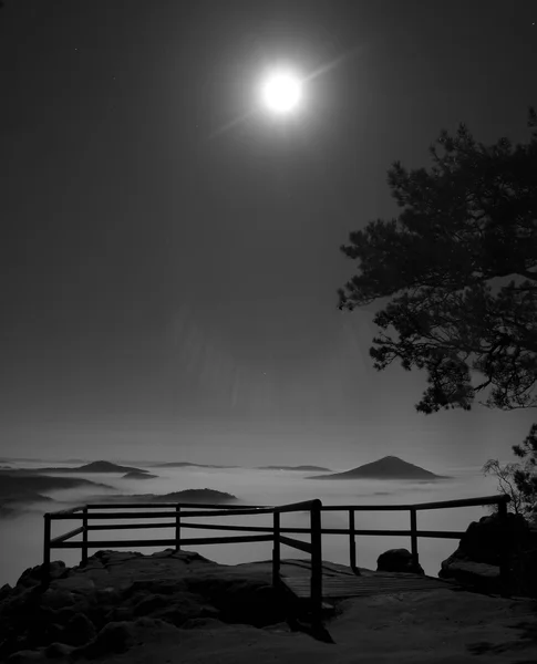 Vollmondnacht mit Sonnenaufgang in einem wunderschönen Berg der böhmisch-sächsischen Schweiz. Sandsteingipfel und Hügel wuchsen aus dem nebligen Hintergrund. Die ersten Sonnenstrahlen. Schwarz-Weiß-Foto. — Stockfoto
