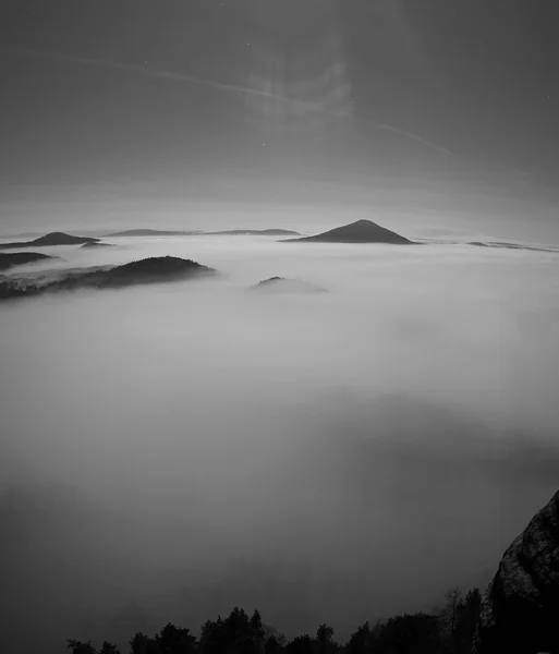 Νύχτα με πανσέληνο με την Ανατολή του ηλίου σε ένα όμορφο βουνό της Βοημίας Σαξονία Ελβετίας. κορυφές ψαμμίτη και λόφους αυξήθηκε από το ομιχλώδες φόντο. πρώτες ακτίνες του ήλιου. ασπρόμαυρη φωτογραφία. — Φωτογραφία Αρχείου