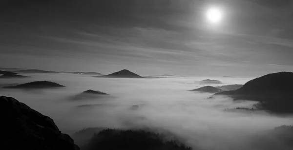 Nuit de pleine lune avec lever de soleil dans une belle montagne de Bohême-Saxe Suisse. Les sommets et les collines de grès ont augmenté à partir du fond brumeux. Premiers rayons du soleil. Photo en noir et blanc . — Photo