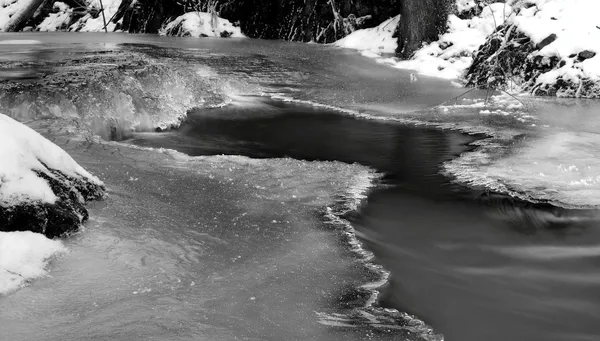 Vue hivernale nocturne sur ruisseau gelé, brindilles glacées et rochers glacés au-dessus du ruisseau rapide. Réflexions de lumière dans les glaçons. Photo en noir et blanc. Gel extrême . — Photo