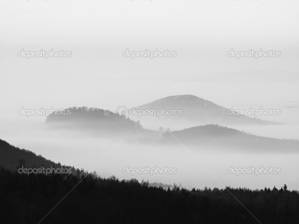 Autumn sunrise in a beautiful mountain of Bohemia. Peaks of hills increased from fog.
