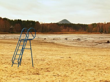 eski mavi çocuklarla boş gölette terk plaj çamurlu ve kirli plaj kumu üzerinde kaydırın. sonbahar melankolik atmosfer.
