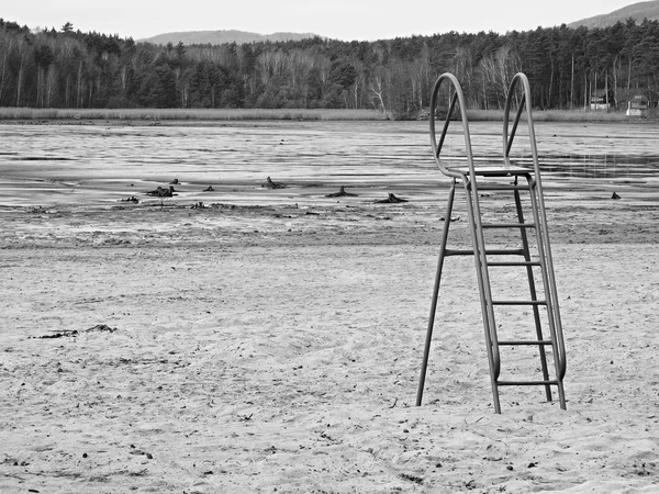 Opuštěná pláž prázdná rybník s staré modré děti klouzat nad bahnité místo a špinavý písek. podzimní melancholická atmosféra. — Stock fotografie