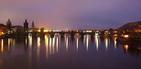 Vista panorámica nocturna sobre el río al viejo puente de piedra entre las partes históricas de la ciudad — Foto de Stock