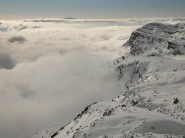 Kayak merkezindeki dağların zirvesi alçak sisten sarkıyor. Ters hava, taze toz kar ve mavi gökyüzü..