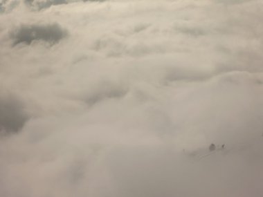 Kayak merkezindeki dağların zirvesi alçak sisten sarkıyor. Ters hava, taze toz kar ve mavi gökyüzü..