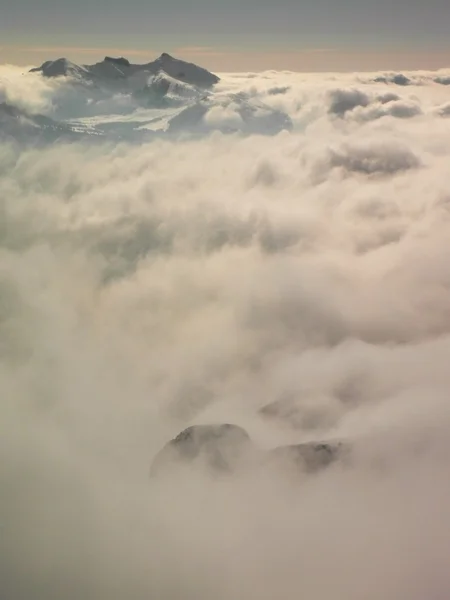 El pico de montañas en la estación de esquí sobresale de la niebla baja. Tiempo de inversión, nieve fresca en polvo y cielo azul . —  Fotos de Stock