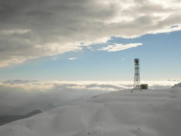 送信機のパイロン、新鮮な粉の雪の山のピーク. — ストック写真