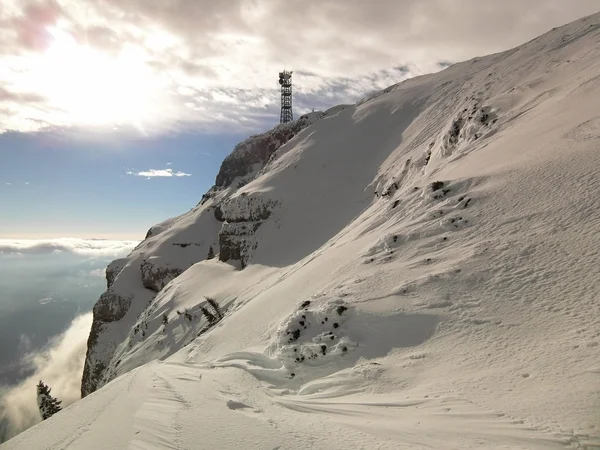 O pico das montanhas na estância de esqui está saindo da névoa baixa . — Fotografia de Stock