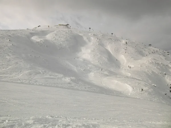 El pico de montañas en la estación de esquí sobresale de la niebla baja. Hermoso día de invierno entre cumbres de los Alpes . — Foto de Stock