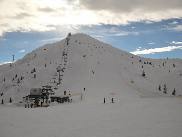 Pico de montaña con ascensor. Camino de cuerda en la estación de esquí, montón de esquiadores disfrutando de nieve fresca en polvo en la pendiente . — Foto de Stock