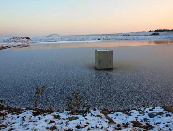 新鲜的粉雪雪花落在小池塘的冰冻水位上。晚上在冬天农村. — 图库照片