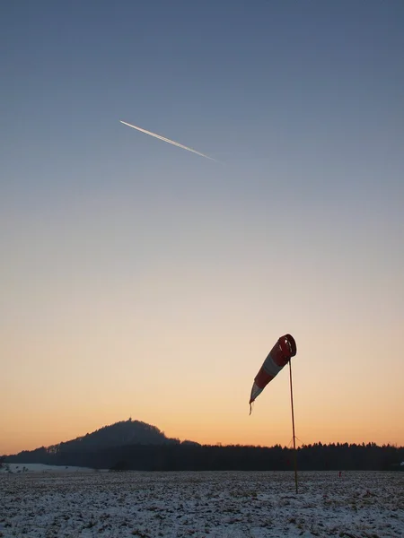 Abandoned winter airport wit windsock, evening blue sky with plane trail — Stock Photo, Image