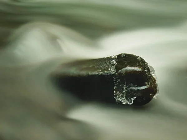 Großer Stein mit kleinen Eiszapfen im milchig verschwommenen Wasser des Gebirgsbaches. Kaltes Winterwetter — Stockfoto