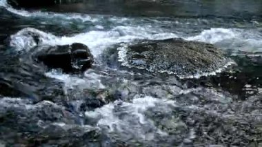 dağ çayı ile ilk toz kar kar tanesi büyük kayalar arasında kış zamanında koyu soğuk su.