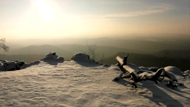 Reeze tronco caído cubierto de nieve fresca en polvo, pico de roca pedregosa aumentó de valle brumoso. Amanecer brumoso de invierno en un hermoso imperio de rocas . — Vídeo de stock