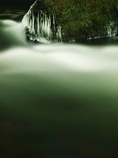 Koyu yeşil soğuk su kış dağ dere, küçük buz sarkıtları sütlü su seviyesinin üzerinde asılı olan. — Stok fotoğraf