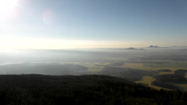 Tepeden aşağı hafif sis ile kırsal görüntüleyin. geniş alanlar, ormanlar, köy ve içinde sabah sunrise hills. — Stok video