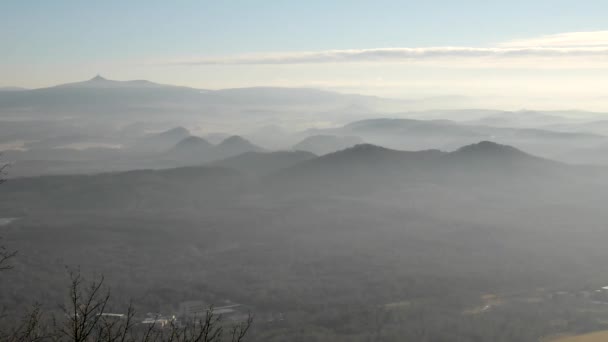 Tepeden aşağı hafif sis ile kırsal görüntüleyin. geniş alanlar, ormanlar, köy ve içinde sabah sunrise hills. — Stok video