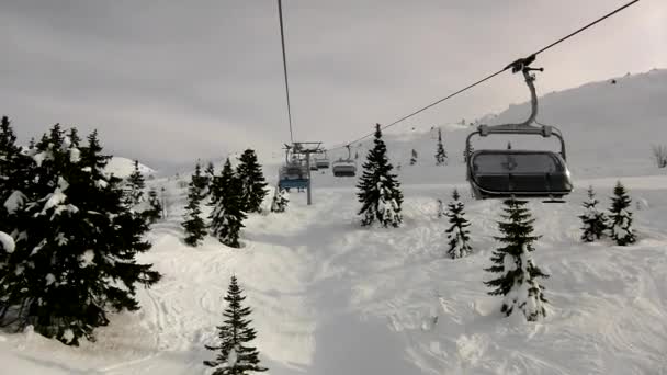 Visa från linbanan ner till utförsåkning och snö ombordstigning på en snöig backe i Alperna skidort. — Stockvideo