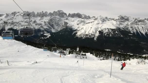 Blick von der Seilbahn hinunter zum Skifahren und Snowboarden auf einer schneebedeckten Piste im alpinen Skigebiet. — Stockvideo