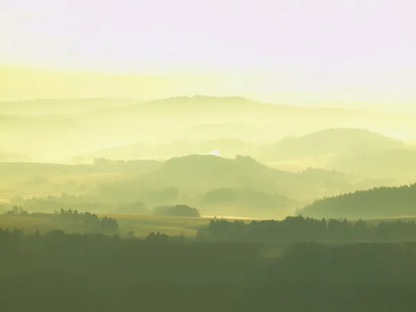 Golden autumn sunrise in a beautiful mountain of Bohemia. Peaks of hills increased from foggy background, the fog is yellow and orange due to sun rays. — Stock Photo, Image