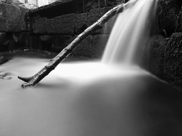 Cascade on small mountain stream, water is running over mossy sandstone boulders and bubbles create on level milky water. Fallen leaves on stones and into water. Black and White photo. — Stock Photo, Image