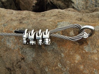 Iron twisted rope fixed in block by screws snaphooks. Detail of rope end anchored into sandstone rock. clipart