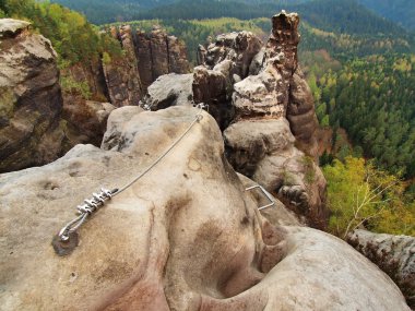 Easy via ferrata in sandstone rock of Saxony Switzerland. Iron twisted rope fixed in block by screws snap hooks. clipart