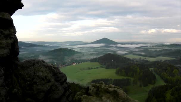 View into foggy vlley below view point in Bohemian Saxony Switzerland. The fog is moving between hills and peaks of trees and makes with sun rays gentle reflections. — Stock Video