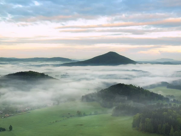 Valle brumoso de primavera después de la noche lluviosa. La niebla se mueve entre colinas y picos de árboles, nubes azules en el cielo . — Foto de Stock