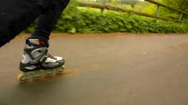 bacaklar ile siyah kırmızı beyaz paten spor giyim gülümsemek görünümüne. adam hızla blading asfalt yolda Park, çim ve yere bırakır.